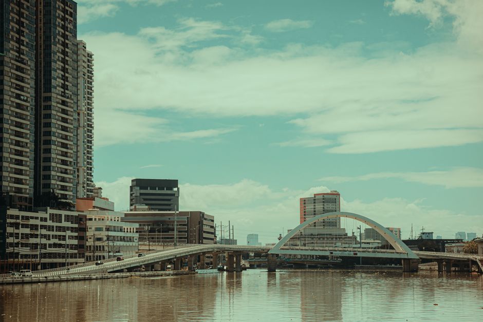 Infraestrutura Manaus — Scenic urban cityscape featuring a modern bridge and skyscrapers reflecting in calm waters.